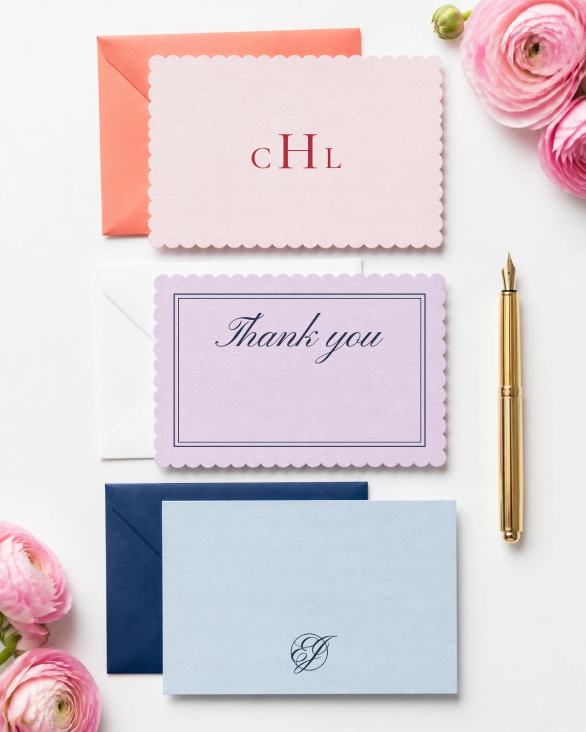 Three note cards: a blush scalloped card with a red CHL monogram on a coral envelope, a lavender scalloped card reading Thank you in navy script inside a navy double border on a white envelope, and a sky blue card with an interlocked EJ monogram on a navy envelope